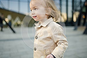Funny toddler boy having fun outdoors on sunny spring day. Child in the city. Kid playing in a city park