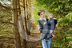 Funny toddler boy and his older sister having fun outdoors on sunny autumn day. Teenage sister cuddling with her little brother