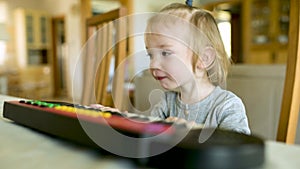 Funny toddler boy playing toy piano at home