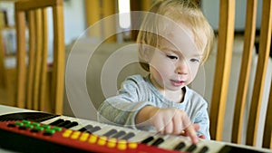 Funny toddler boy playing toy piano at home