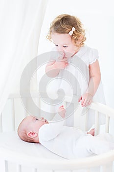 Funny toddler girl hushing her newborn baby brother