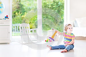 Funny toddler girl with pyramid toy in white room
