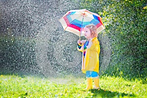 Funny toddler with umbrella playing in the rain