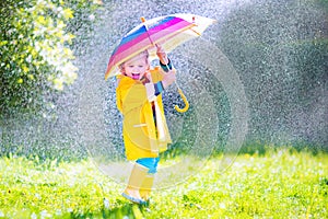 Funny toddler with umbrella playing in the rain