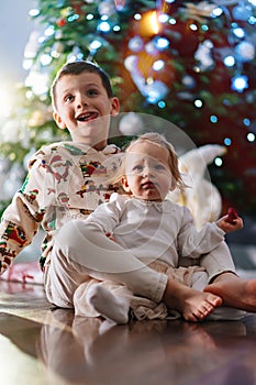 funny toddlers brother and sister at the Christmas tree. holiday for children.