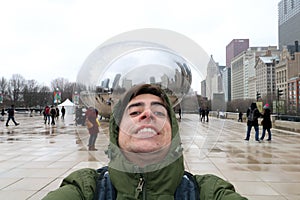 Funny tourist at Cloud gate at Chicago Illinois Bean mirror art with people and buildings.