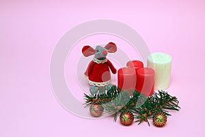 Funny toy red mouse, the symbol of the Chinese New Year 2020 on a pink background, red, white candles, balls, Christmas tree