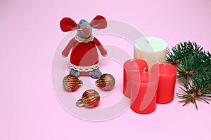 Funny toy red mouse, the symbol of the Chinese New Year 2020 on a pink background, red, white candles, balls, Christmas tree
