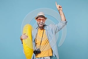 Funny traveler tourist man in yellow clothes, eyeglasses with photo camera isolated on blue background. Passenger