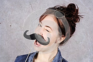 Funny trendy fashion girl with paper mustache playing with emotion