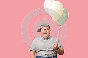 Funny tubby guy with positive emotions smiling happily, holding air balloons. photo