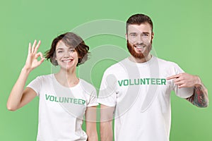 Funny two young friends couple in white volunteer t-shirt isolated on pastel green background studio portrait. Voluntary