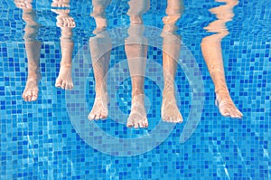 Funny underwater family legs in swimming pool, under water view of mother and kids, vacation and sport