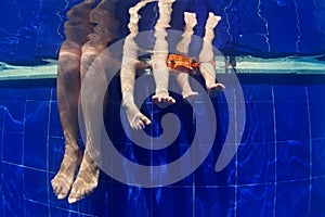 Funny underwater photo mother with kids legs in swimming pool
