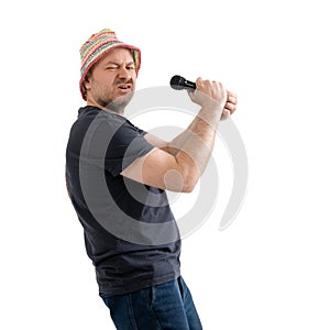 A funny unshaven man 40 years old in a bright hat holds a microphone in his hands. Isolated on a white background