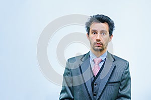 Funny unshaven man in suit with tie on gray background