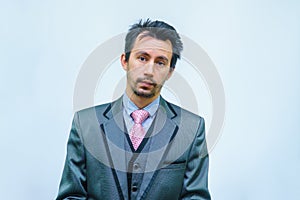 Funny unshaven man in suit with tie on gray background
