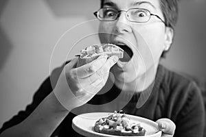 Funny Upclose view of caucasian woman eating avocado toast looking into camera, horizontal black and white shot