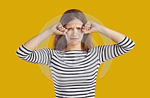 Funny upset young woman isolated on yellow background crying and rubbing her eyes