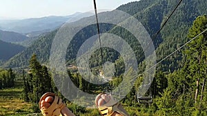 Funny video from the cable car. Girl in summer sandals dancing feet admiring the beautiful views of the forest and mountains.