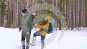 Funny video. A young man and a girl are walking along a winter forest path.