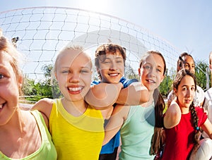 Funny view of teens standing near volleyball net