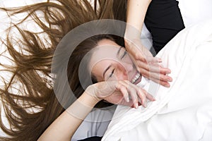 Funny wakening. Young woman is lying in her bed, smiling and joking.