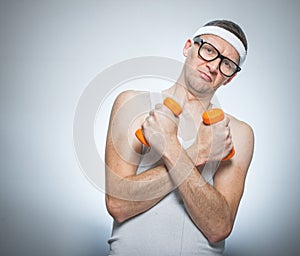 Funny weak man holding dumbbells