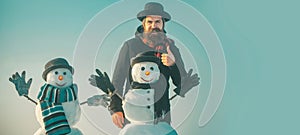 Funny winter snow man in hat play with snowman outdoor. Man with snowman on winter outdoor background. Snow man for