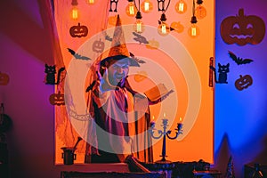 Funny wise wizard on a Halloween background. Wizard, sorcerer, warlock. Mystery and horror concept. Jack o lantern.