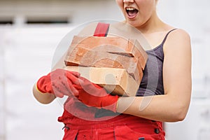 Funny woman carrying heavy bricks