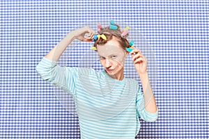 Funny woman with colorful hair curlers, and skincare product on face