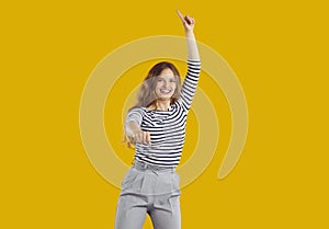 Portrait of happy funny young girl dancing and jumping isolated on yellow background