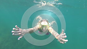 Funny woman diver in a mask swims in the sea underwater