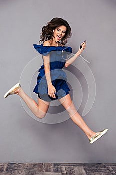 Funny woman in dress listening music and jumping