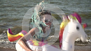Funny woman in an inflatable ring at the sea. Cheerful woman in a swimming circle dancing on the beach
