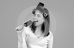 Funny woman singing with comb. Beautiful young woman holding healthy and shiny hair, studio. Closeup on young woman