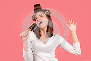 Funny woman singing with comb. Girl combing hair. Beautiful young woman holding comb straightened hair.