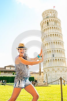 Funny woman supporting leaning tower of pisa