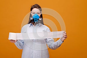 funny woman with with toilet paper in hand in protective equipment in medical mask on yellow background, coronavirus pandemic,