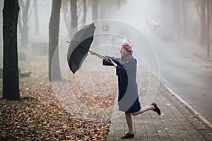 A funny woman with an umbrella in foggy weather.