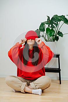 Funny woman in vibrant red clothes with cap lowered over her eyes.