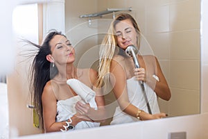 Funny women singing in bathroom having fun.