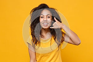 Funny young african american woman girl in casual t-shirt posing isolated on yellow orange background in studio. People