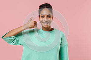 Funny young african american woman girl in green sweatshirt posing isolated on pastel pink background in studio. People
