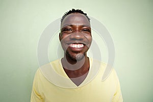 Funny young african man smiling against green wall