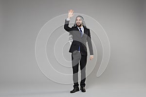 Funny young arabian muslim businessman in keffiyeh kafiya ring igal agal suit isolated on gray background. Achievement