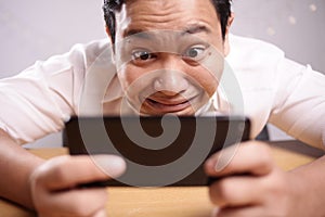 Funny Young Asian Guy Playing Games on Tablet