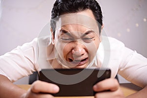 Funny Young Asian Guy Playing Games on Tablet