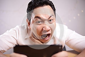 Funny Young Asian Guy Playing Games on Tablet